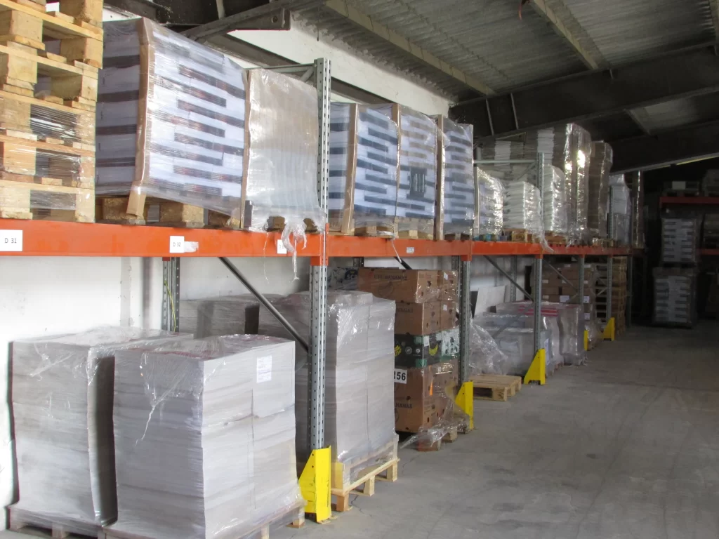 A beérkezett papír- és kartonáruk raklapokra helyezve, korszerű állványrendszeren tárolva várnak feldolgozásra a Palota-15 Nonprofit Kft raktárcsarnokában.